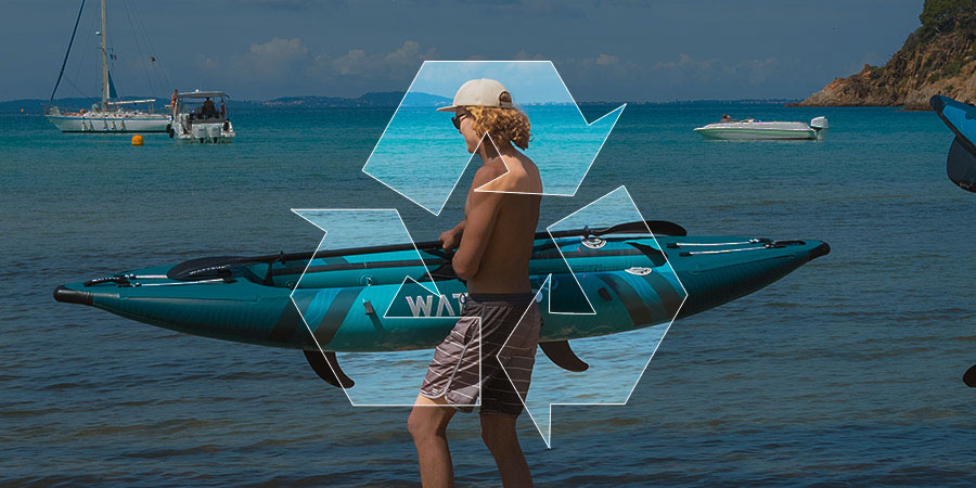Jeune homme à la plage tenant son kayak gonflable avec un grand symbole de recyclage en premier-plan